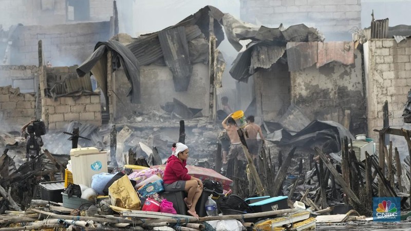 A Philippine Air Force helicopter drops water on burning homes as fire broke out at a slum area leaving about 2,000 families homeless on Sunday, Nov. 24, 2024 in Manila, Philippines. (AP Photo/Aaron Favila)