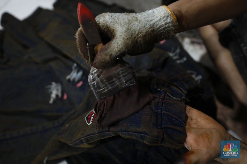 Pekerja menyelesaikan pencucian pakaian jeans di kawasan Jakarta,  Senin (25/11/2024). Pemerintah bakal memberlakukan tarif Pajak Pertambahan Nilai (PPN) sebesar 12% di tahun 2025 nanti. (CNBC Indonesia/Tri Susilo)
