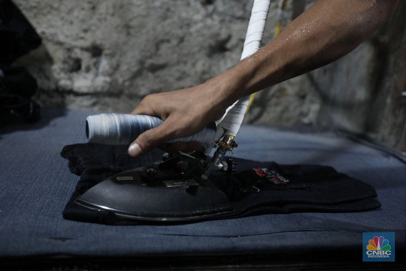 Pekerja menyelesaikan pencucian pakaian jeans di kawasan Jakarta,  Senin (25/11/2024). Pemerintah bakal memberlakukan tarif Pajak Pertambahan Nilai (PPN) sebesar 12% di tahun 2025 nanti. (CNBC Indonesia/Tri Susilo)