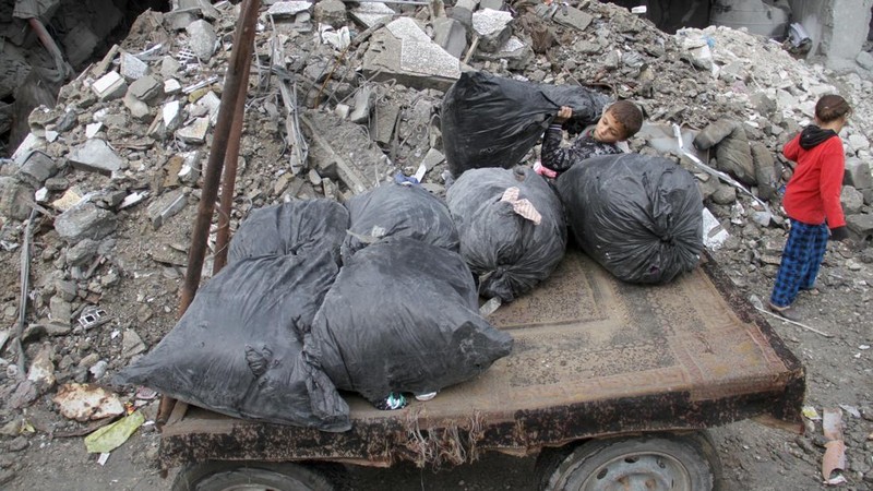 A Palestinian boy loads onto a cart items recovered from the rubble at the site of an Israeli attack on a house, during the ongoing conflict between Israel and Hamas, in Gaza City, November 26, 2024. REUTERS/Mahmoud Issa