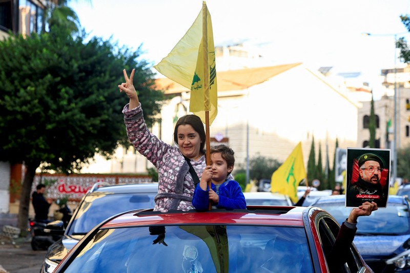 Seseorang memberi isyarat sambil memegang poster bergambar mendiang pemimpin Hizbullah Sayyed Hassan Nasrallah, di pintu masuk pinggiran selatan Beirut, setelah gencatan senjata antara Israel dan kelompok Hizbullah yang didukung Iran mulai berlaku pada pukul 02.00 GMT pada hari Rabu setelah Presiden AS Joe Biden mengatakan kedua belah pihak menerima perjanjian yang ditengahi oleh Amerika Serikat dan Prancis, di Lebanon, 27 November 2024. Seseorang memberi isyarat sambil memegang poster bergambar mendiang pemimpin Hizbullah Sayyed Hassan Nasrallah, di pintu masuk pinggiran selatan Beirut, setelah gencatan senjata antara Israel dan kelompok Hizbullah yang didukung Iran mulai berlaku pada pukul 02.00 GMT pada hari Rabu setelah Presiden AS Joe Biden mengatakan kedua belah pihak menerima perjanjian yang ditengahi oleh Amerika Serikat dan Prancis, di Lebanon, 27 November 2024. (REUTERS/Thaier Al-Sudani)