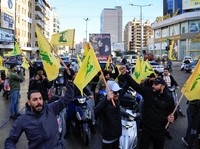 Men gesture while holding Hezbollah flags, at the entrance of Beirut's southern suburbs, after a ceasefire between Israel and Iran-backed group Hezbollah took effect at 0200 GMT on Wednesday after U.S. President Joe Biden said both sides accepted an