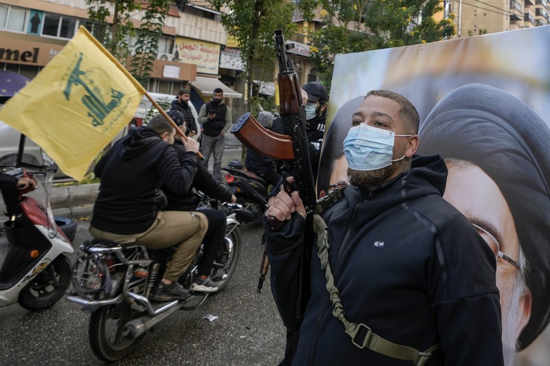Men carry Hezbollah flags and a picture depicting late Hezbollah leader Sayyed Hassan Nasrallah, as they drive past damaged buildings at the entrance of Beirut's southern suburbs, after a ceasefire between Israel and Hezbollah took effect, Lebanon November 27, 2024. REUTERS/Mohamed Azakir     TPX IMAGES OF THE DAY