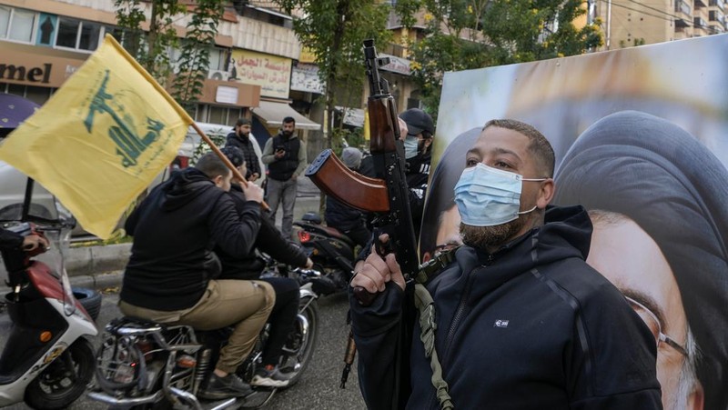 Men carry Hezbollah flags and a picture depicting late Hezbollah leader Sayyed Hassan Nasrallah, as they drive past damaged buildings at the entrance of Beirut's southern suburbs, after a ceasefire between Israel and Hezbollah took effect, Lebanon November 27, 2024. REUTERS/Mohamed Azakir     TPX IMAGES OF THE DAY