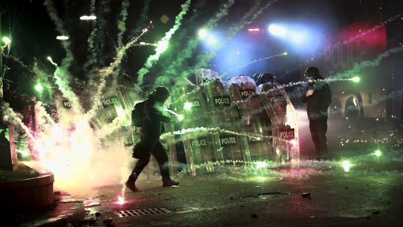 Para demonstran menggunakan petasan terhadap polisi saat polisi memblokir jalan untuk mencegah pengunjuk rasa berunjuk rasa menentang keputusan pemerintah untuk menangguhkan negosiasi untuk bergabung dengan Uni Eropa selama empat tahun, di luar gedung parlemen di Tbilisi, Georgia, Sabtu dini hari, 30 November 2024. (AP Photo/Zurab Tsertsvadze)