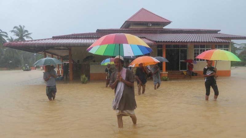 Para pria berjalan melewati banjir setelah menunaikan salat di sebuah masjid di Hulu Terengganu, Malaysia, 29 November 2024. (REUTERS/ Stringer)