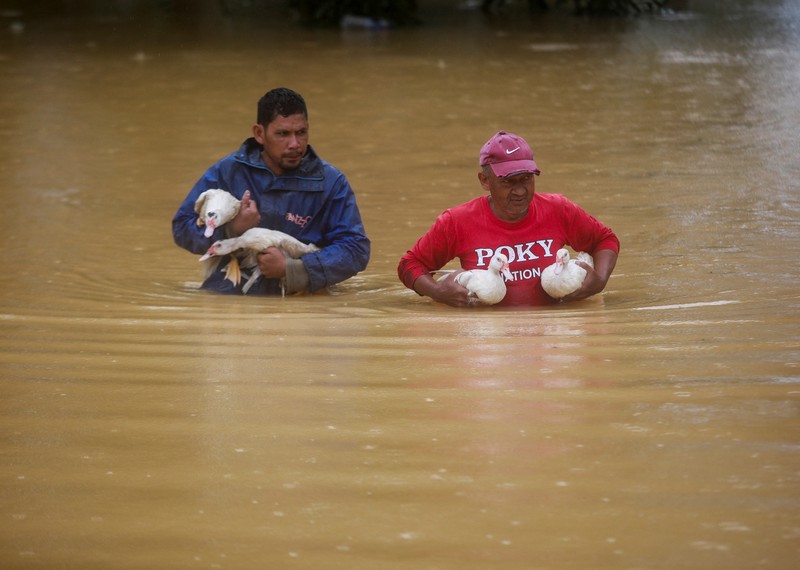 Para pria berjalan melewati banjir setelah menunaikan salat di sebuah masjid di Hulu Terengganu, Malaysia, 29 November 2024. (REUTERS/ Stringer)