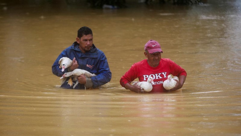 Para pria berjalan melewati banjir setelah menunaikan salat di sebuah masjid di Hulu Terengganu, Malaysia, 29 November 2024. (REUTERS/ Stringer)