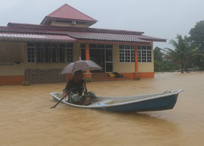 Para pria berjalan melewati banjir setelah menunaikan salat di sebuah masjid di Hulu Terengganu, Malaysia, 29 November 2024. (REUTERS/ Stringer)