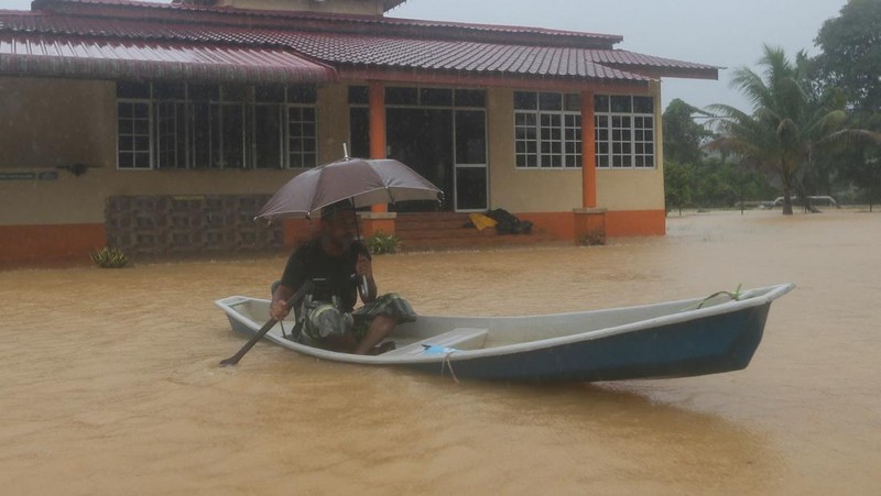 Para pria berjalan melewati banjir setelah menunaikan salat di sebuah masjid di Hulu Terengganu, Malaysia, 29 November 2024. (REUTERS/ Stringer)