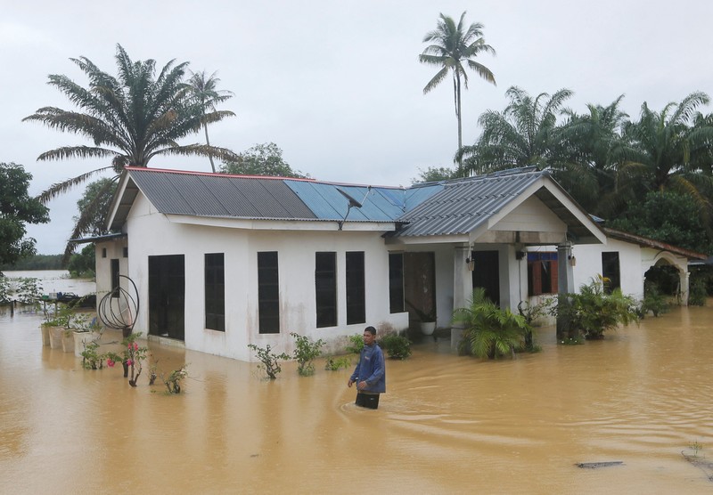 Para pria berjalan melewati banjir setelah menunaikan salat di sebuah masjid di Hulu Terengganu, Malaysia, 29 November 2024. (REUTERS/ Stringer)