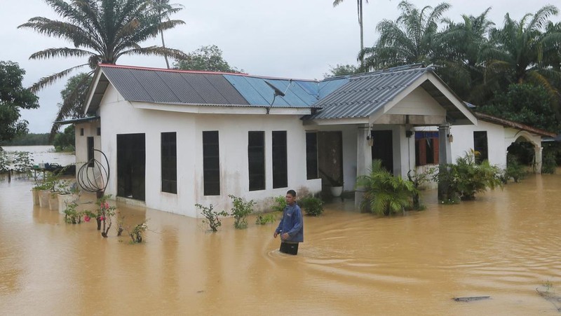 Para pria berjalan melewati banjir setelah menunaikan salat di sebuah masjid di Hulu Terengganu, Malaysia, 29 November 2024. (REUTERS/ Stringer)