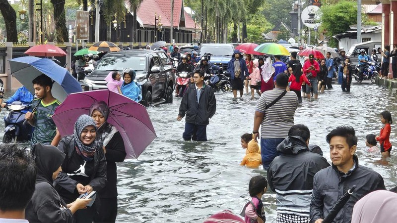 Para pria berjalan melewati banjir setelah menunaikan salat di sebuah masjid di Hulu Terengganu, Malaysia, 29 November 2024. (REUTERS/ Stringer)