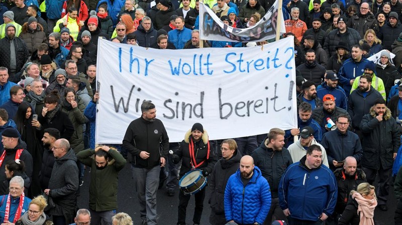 Para pekerja pabrikan mobil asal Jerman, Volkswagen melakukan membawa bendera saat mereka melakukan mogok kerja di Hanover, Jerman, Senin (2/12/2024). (REUTERS/Fabian Bimmer)