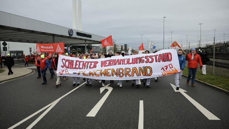 Para pekerja pabrikan mobil asal Jerman, Volkswagen melakukan membawa bendera saat mereka melakukan mogok kerja di Hanover, Jerman, Senin (2/12/2024). (REUTERS/Fabian Bimmer)