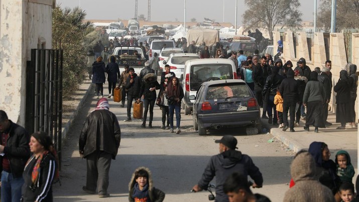 Orang-orang terlantar yang melarikan diri dari pedesaan Aleppo berjalan melewati mobil-mobil di Tabqa, Suriah, 4 Desember 2024. (REUTERS/Orhan Qereman)