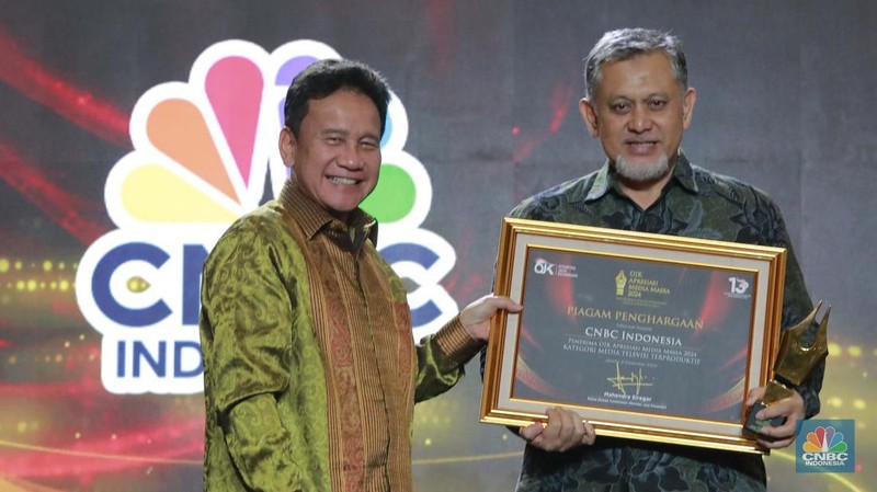 Wakil Ketua Dewan Komisioner OJK Mirza Adityaswara memberi penghargaan kepada Direktur CNBC Indonesia Shanta Curanggana dalam kategori Media Televisi Terproduktif untuk media CNBC Indonesia dalam acara OJK Apresiasi Media Massa 2024 di Hotel Ritz Carlton, Jakarta, Jumat (6/12/2024). (CNBC Indonesia/Muhammad Sabki)