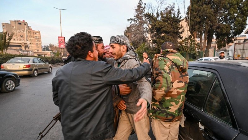 Orang- orang berkumpul di alun-alun utama Damaskus sambil melambaikan tangan dan meneriakkan 'Kebebasan' dari pemerintahan keluarga Assad yang telah berkuasa sekitar 50 tahun. (Photo by LOUAI BESHARA / AFP)