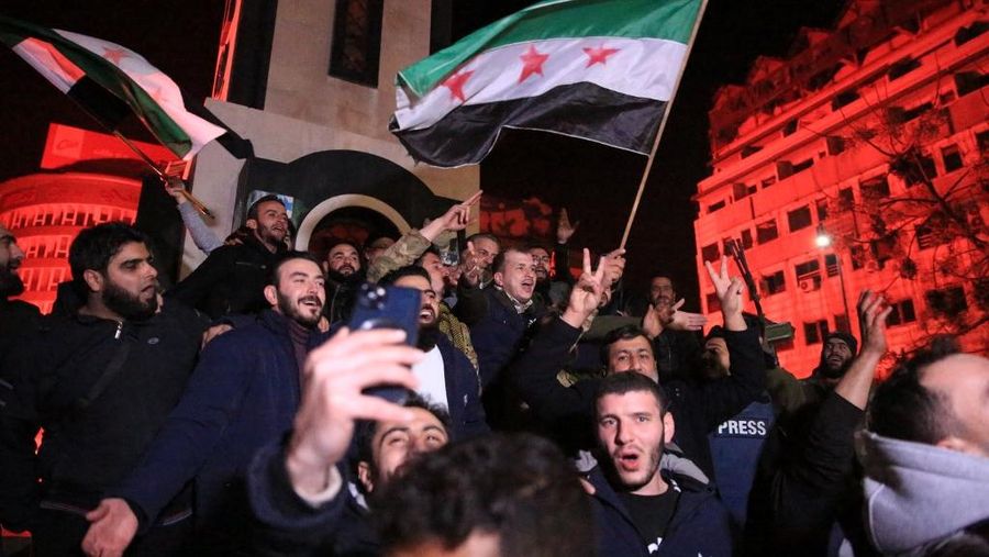 Orang- orang berkumpul di alun-alun utama Damaskus sambil melambaikan tangan dan meneriakkan 'Kebebasan' dari pemerintahan keluarga Assad yang telah berkuasa sekitar 50 tahun. (Photo by LOUAI BESHARA / AFP)