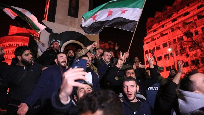 Orang- orang berkumpul di alun-alun utama Damaskus sambil melambaikan tangan dan meneriakkan 'Kebebasan' dari pemerintahan keluarga Assad yang telah berkuasa sekitar 50 tahun. (Photo by LOUAI BESHARA / AFP)