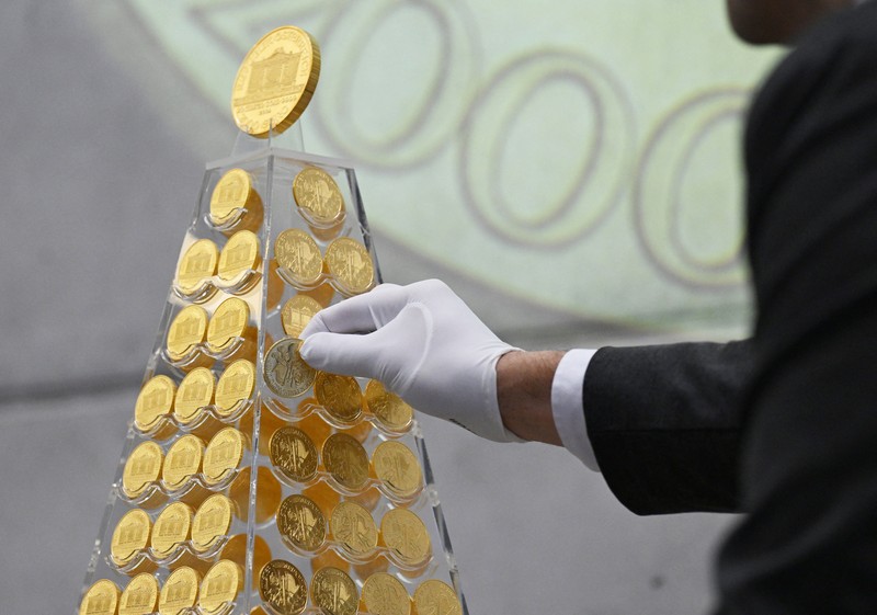 Benjamin Summa, karyawan perusahaan perdagangan emas Munich, meletakkan koin emas di 'Pohon Natal Emas' dengan nilai saat ini sekitar 5,3 juta euro di Munich, Jerman, Selasa, 3 Desember 2024. (Sven Hoppe/dpa/dpa via AP)
