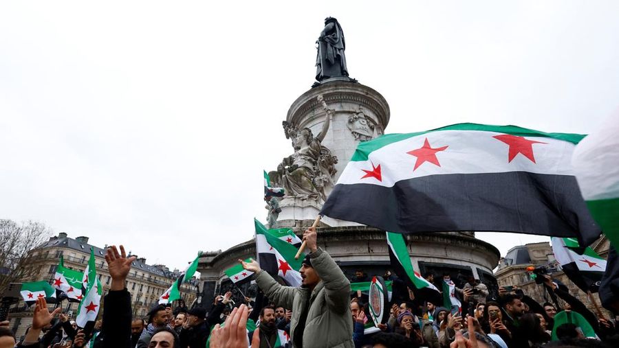 Orang-orang memegang bendera oposisi Suriah saat berkumpul di Place de la Republique, setelah pemberontak Suriah mengumumkan bahwa mereka telah menggulingkan Presiden Bashar al-Assad, di Paris, Prancis, 8 Desember 2024. (REUTERS/Piroschka van de Wouw)