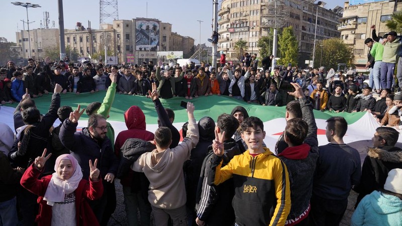 Orang-orang memegang bendera oposisi Suriah saat merayakan, setelah komando tentara Suriah memberi tahu para perwira pada hari Minggu bahwa pemerintahan otoriter Presiden Bashar al-Assad selama 24 tahun telah berakhir, seorang perwira Suriah yang diberitahu tentang tindakan tersebut mengatakan kepada Reuters, menyusul serangan pemberontak cepat yang mengejutkan dunia, di Aleppo, Suriah 8 Desember 2024. (REUTERS/Karam al-Masri)