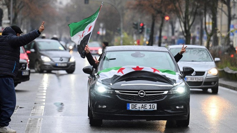 Orang-orang memegang bendera oposisi Suriah saat merayakan, setelah komando tentara Suriah memberi tahu para perwira pada hari Minggu bahwa pemerintahan otoriter Presiden Bashar al-Assad selama 24 tahun telah berakhir, seorang perwira Suriah yang diberitahu tentang tindakan tersebut mengatakan kepada Reuters, menyusul serangan pemberontak cepat yang mengejutkan dunia, di Aleppo, Suriah 8 Desember 2024. (REUTERS/Karam al-Masri)