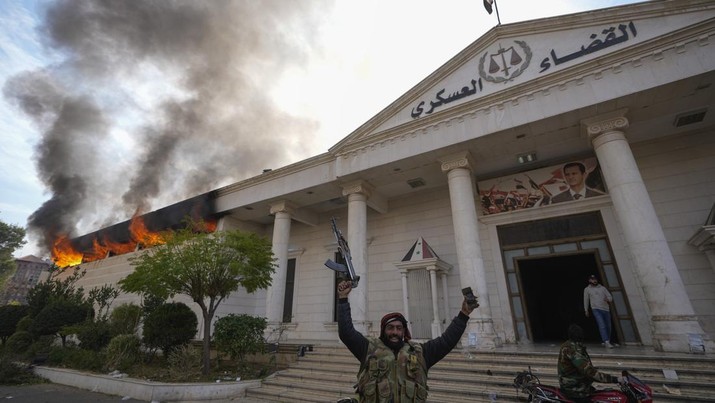 Pejuang oposisi merayakan saat mereka membakar pengadilan militer di Damaskus, Suriah, Minggu, 8 Desember 2024. (AP Photo/Hussein Malla)