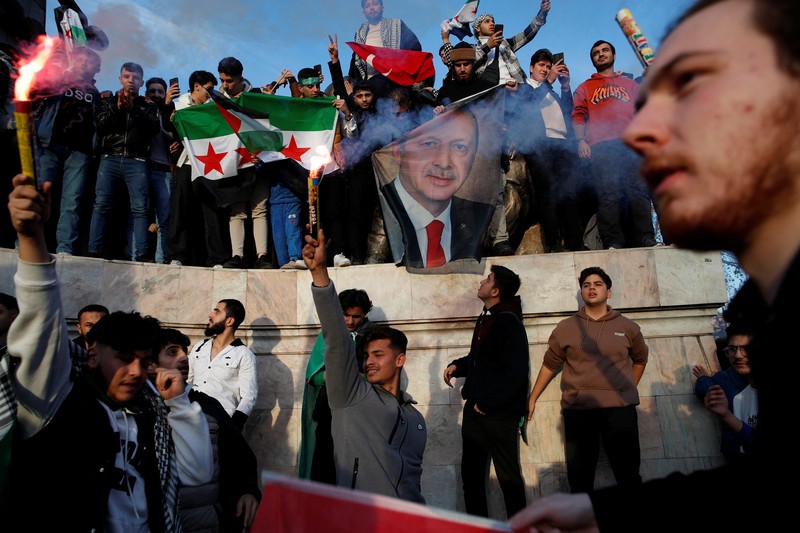 Orang-orang memegang bendera oposisi Suriah saat merayakan, setelah komando tentara Suriah memberi tahu para perwira pada hari Minggu bahwa pemerintahan otoriter Presiden Bashar al-Assad selama 24 tahun telah berakhir, seorang perwira Suriah yang diberitahu tentang tindakan tersebut mengatakan kepada Reuters, menyusul serangan pemberontak cepat yang mengejutkan dunia, di Aleppo, Suriah 8 Desember 2024. (REUTERS/Karam al-Masri)