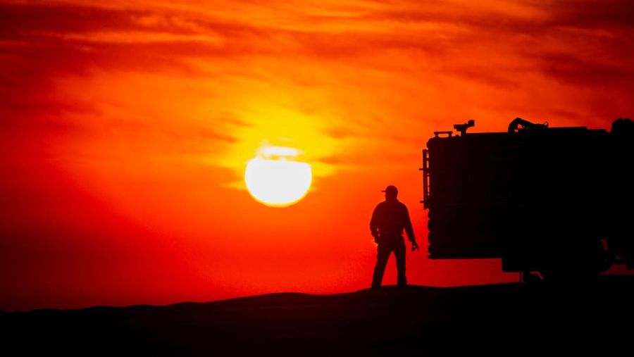 Siluet seorang petugas pemadam kebakaran berdiri di samping mobil pemadam kebakaran saat matahari terbenam ketika Kebakaran Franklin berkobar di Malibu, California, AS, 10 Desember 2024. (REUTERS/Ringo Chiu)