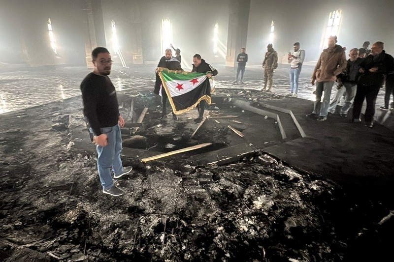 Kombinasi visual yang dibuat pada (11/12/2024) ini menunjukkan gambar (atas) yang diambil pada hari yang sama dari pejuang pemberontak yang berdiri dengan bendera oposisi di makam mendiang presiden Suriah Hafez al-Assad yang terbakar di makamnya di desa leluhur keluarga Qardaha di provinsi Latakia barat, setelah diserbu oleh faksi anti-Assad dan dibakar dan gambar arsip lain yang dirilis oleh Kantor Berita Arab Suriah (SANA) pada (16/11/2011) dari warga Suriah yang mengunjungi makam yang sama untuk memperingati ulang tahun Kombinasi visual yang dibuat pada (11/12/2024) ini menunjukkan gambar (atas) yang diambil pada hari yang sama dari pejuang pemberontak yang berdiri dengan bendera oposisi di makam mendiang presiden Suriah Hafez al-Assad yang terbakar di makamnya di desa leluhur keluarga Qardaha di provinsi Latakia barat, setelah diserbu oleh faksi anti-Assad dan dibakar dan gambar arsip lain yang dirilis oleh Kantor Berita Arab Suriah (SANA) pada (16/11/2011) dari warga Suriah yang mengunjungi makam yang sama untuk memperingati ulang tahun