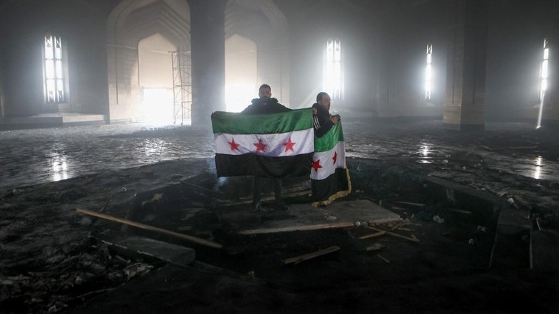 Kombinasi visual yang dibuat pada (11/12/2024) ini menunjukkan gambar (atas) yang diambil pada hari yang sama dari pejuang pemberontak yang berdiri dengan bendera oposisi di makam mendiang presiden Suriah Hafez al-Assad yang terbakar di makamnya di desa leluhur keluarga Qardaha di provinsi Latakia barat, setelah diserbu oleh faksi anti-Assad dan dibakar dan gambar arsip lain yang dirilis oleh Kantor Berita Arab Suriah (SANA) pada (16/11/2011) dari warga Suriah yang mengunjungi makam yang sama untuk memperingati ulang tahun 