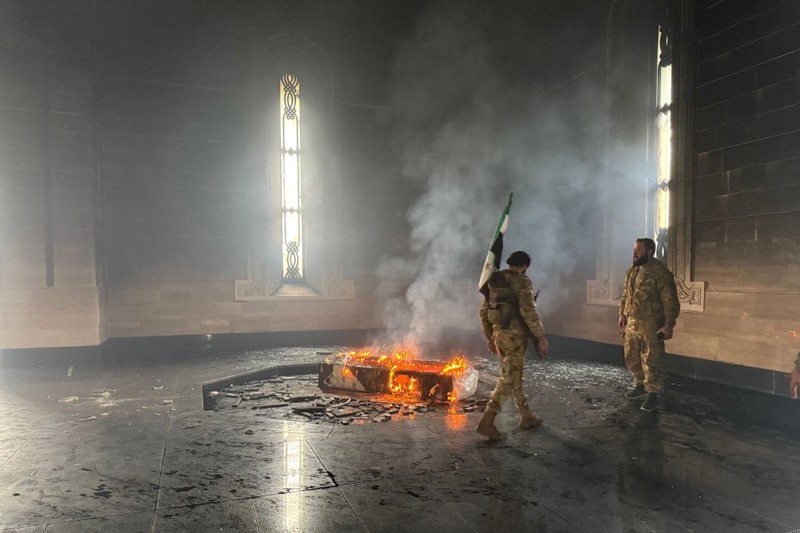 Kombinasi visual yang dibuat pada (11/12/2024) ini menunjukkan gambar (atas) yang diambil pada hari yang sama dari pejuang pemberontak yang berdiri dengan bendera oposisi di makam mendiang presiden Suriah Hafez al-Assad yang terbakar di makamnya di desa leluhur keluarga Qardaha di provinsi Latakia barat, setelah diserbu oleh faksi anti-Assad dan dibakar dan gambar arsip lain yang dirilis oleh Kantor Berita Arab Suriah (SANA) pada (16/11/2011) dari warga Suriah yang mengunjungi makam yang sama untuk memperingati ulang tahun Kombinasi visual yang dibuat pada (11/12/2024) ini menunjukkan gambar (atas) yang diambil pada hari yang sama dari pejuang pemberontak yang berdiri dengan bendera oposisi di makam mendiang presiden Suriah Hafez al-Assad yang terbakar di makamnya di desa leluhur keluarga Qardaha di provinsi Latakia barat, setelah diserbu oleh faksi anti-Assad dan dibakar dan gambar arsip lain yang dirilis oleh Kantor Berita Arab Suriah (SANA) pada (16/11/2011) dari warga Suriah yang mengunjungi makam yang sama untuk memperingati ulang tahun