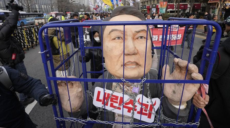 Para pengunjuk rasa membawa karikatur yang menggambarkan Presiden Korea Selatan Yoon Suk Yeol yang dipenjara saat mereka berbaris menuju kantor presiden setelah unjuk rasa menuntut pemakzulannya di Seoul, Korea Selatan, Kamis, 12 Desember 2024. Sebuah tanda bertuliskan 