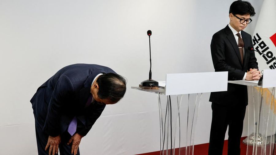 Perdana Menteri Korea Selatan Han Duck-soo membungkuk untuk meminta maaf sambil berdiri di dekat pemimpin Partai Kekuatan Rakyat yang berkuasa Han Dong Hoon saat mereka merilis pernyataan publik bersama setelah pemungutan suara pemakzulan terhadap presiden gagal, di kantor pusat partai di Seoul, Korea Selatan, 8 Desember 2024. (REUTERS/Kim Kyung-Hoon)
