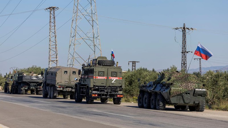 Seorang tentara Rusia berpatroli terhadap konvoi militer di pinggir jalan karena kerusakan mesin di salah satu kendaraan saat mereka melakukan perjalanan melalui pangkalan udara Hmeimim di wilayah pesisir Latakia, Suriah, 14 Desember 2024. (REUTERS/Umit Bektas)