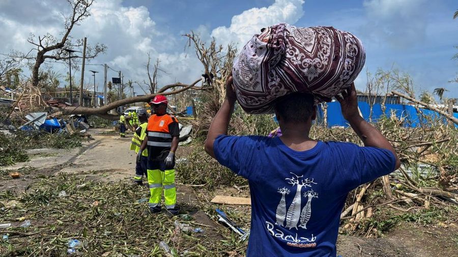A man carries his belongings as rescue workers attempt to clear a blocked road, in the aftermath of Cyclone Chido, within Labattoir, in Mayotte, France, December 15, 2024. REUTERS/Chafion Madi