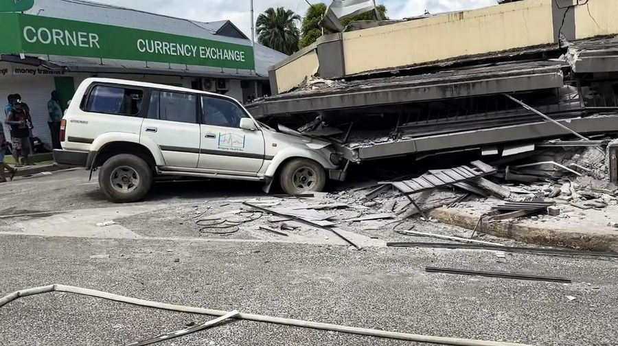 Pasukan keamanan dan penyelamat memeriksa mobil rusak yang terjebak di bawah bangunan yang runtuh di ibu kota Vanuatu, Port Vila, setelah gempa bumi dahsyat melanda dengan magnitudo 7,3M. (Photo by MICHAEL THOMPSON / Facebook account of Michael Thompson / AFP)