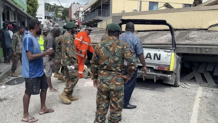 Pasukan keamanan dan penyelamat memeriksa mobil rusak yang terjebak di bawah bangunan yang runtuh di ibu kota Vanuatu, Port Vila, setelah gempa bumi dahsyat melanda dengan magnitudo 7,3M. (Photo by MICHAEL THOMPSON / Facebook account of Michael Thompson / AFP)