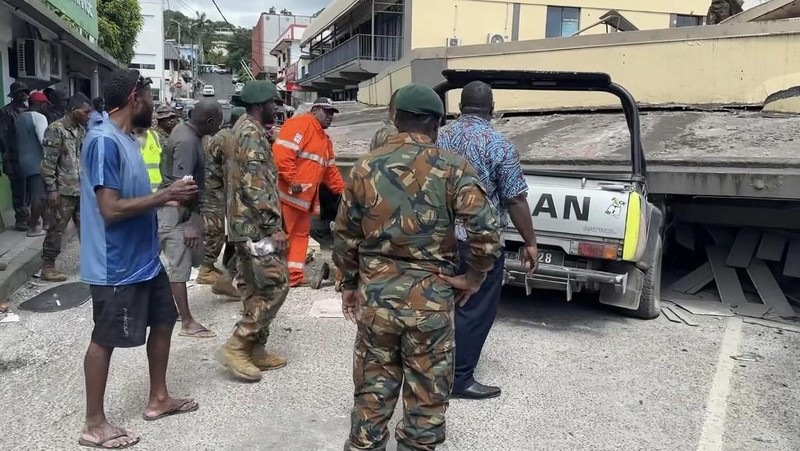Pasukan keamanan dan penyelamat memeriksa mobil rusak yang terjebak di bawah bangunan yang runtuh di ibu kota Vanuatu, Port Vila, setelah gempa bumi dahsyat melanda dengan magnitudo 7,3M. (Photo by MICHAEL THOMPSON / Facebook account of Michael Thompson / AFP)