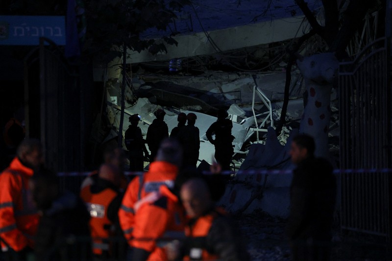 Personel layanan darurat bekerja di dekat lokasi yang rusak setelah proyektil yang ditembakkan dari Yaman dicegat, di Ramat Gan, Israel, 19 Desember 2024. (REUTERS/Stoyan Nenov)
