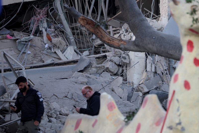 Personel layanan darurat bekerja di dekat lokasi yang rusak setelah proyektil yang ditembakkan dari Yaman dicegat, di Ramat Gan, Israel, 19 Desember 2024. (REUTERS/Stoyan Nenov)