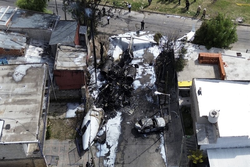 Puing-puing pesawat pribadi tergeletak di samping rumah-rumah setelah jatuh di dekat bandara di San Fernando di pinggiran Buenos Aires, Argentina, Rabu, 18 Desember 2024. (AP Photo/Natacha Pisarenko)