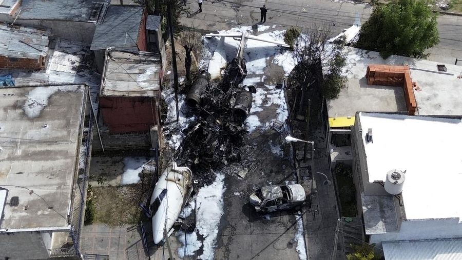 Puing-puing pesawat pribadi tergeletak di samping rumah-rumah setelah jatuh di dekat bandara di San Fernando di pinggiran Buenos Aires, Argentina, Rabu, 18 Desember 2024. (AP Photo/Natacha Pisarenko)