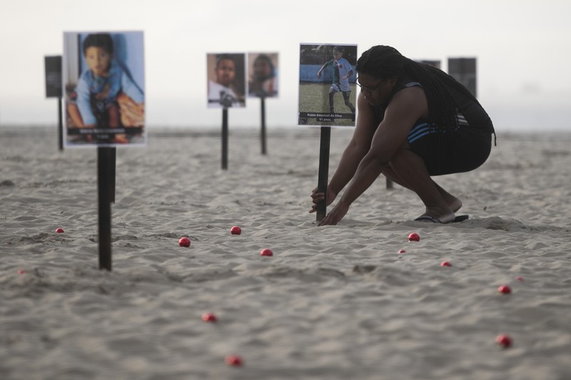 Seorang wanita berlari melewati 48 gambar anak-anak yang ditembak mati selama operasi polisi selama pemerintahan gubernur Rio de Janeiro Claudio Castro, oleh LSM Rio de Paz, di pantai Copacabana di Rio de Janeiro, Brasil, 18 Desember 2024. (REUTERS/Pilar Olivares)