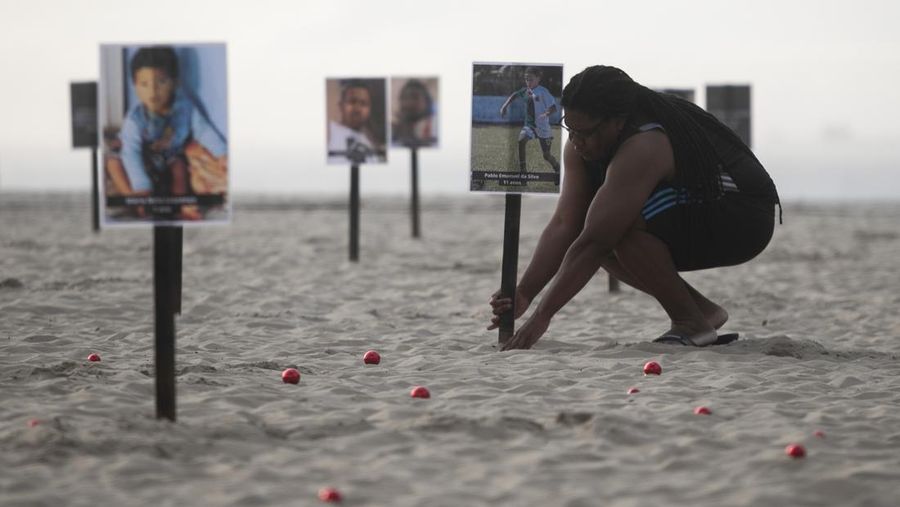 Seorang wanita berlari melewati 48 gambar anak-anak yang ditembak mati selama operasi polisi selama pemerintahan gubernur Rio de Janeiro Claudio Castro, oleh LSM Rio de Paz, di pantai Copacabana di Rio de Janeiro, Brasil, 18 Desember 2024. (REUTERS/Pilar Olivares)