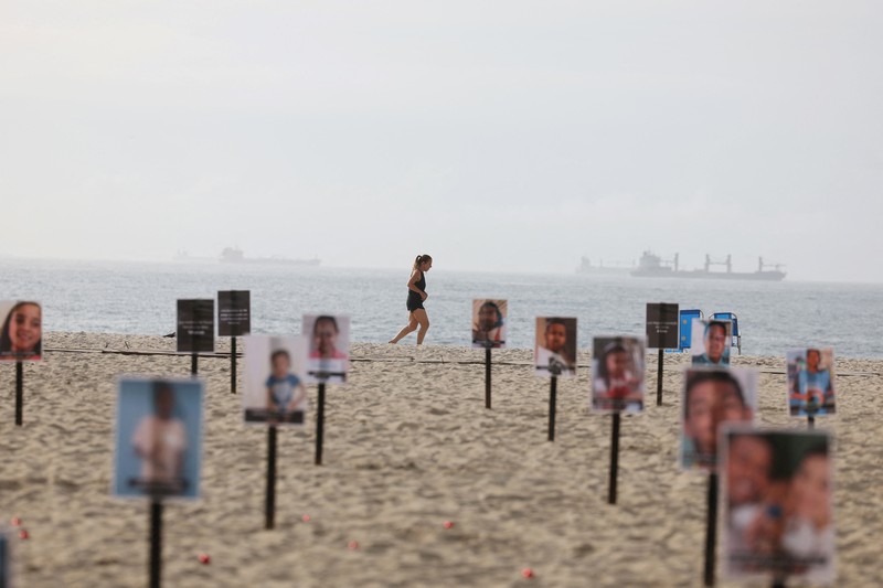 Seorang wanita berlari melewati 48 gambar anak-anak yang ditembak mati selama operasi polisi selama pemerintahan gubernur Rio de Janeiro Claudio Castro, oleh LSM Rio de Paz, di pantai Copacabana di Rio de Janeiro, Brasil, 18 Desember 2024. Seorang wanita berlari melewati 48 gambar anak-anak yang ditembak mati selama operasi polisi selama pemerintahan gubernur Rio de Janeiro Claudio Castro, oleh LSM Rio de Paz, di pantai Copacabana di Rio de Janeiro, Brasil, 18 Desember 2024. (REUTERS/Pilar Olivares)