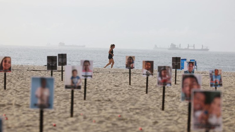 Seorang wanita berlari melewati 48 gambar anak-anak yang ditembak mati selama operasi polisi selama pemerintahan gubernur Rio de Janeiro Claudio Castro, oleh LSM Rio de Paz, di pantai Copacabana di Rio de Janeiro, Brasil, 18 Desember 2024. (REUTERS/Pilar Olivares)