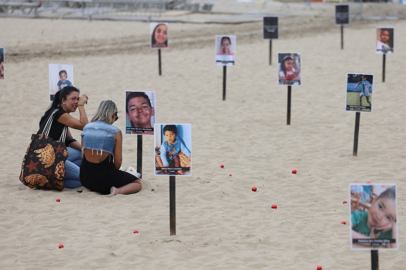 Seorang wanita berlari melewati 48 gambar anak-anak yang ditembak mati selama operasi polisi selama pemerintahan gubernur Rio de Janeiro Claudio Castro, oleh LSM Rio de Paz, di pantai Copacabana di Rio de Janeiro, Brasil, 18 Desember 2024. (REUTERS/Pilar Olivares)